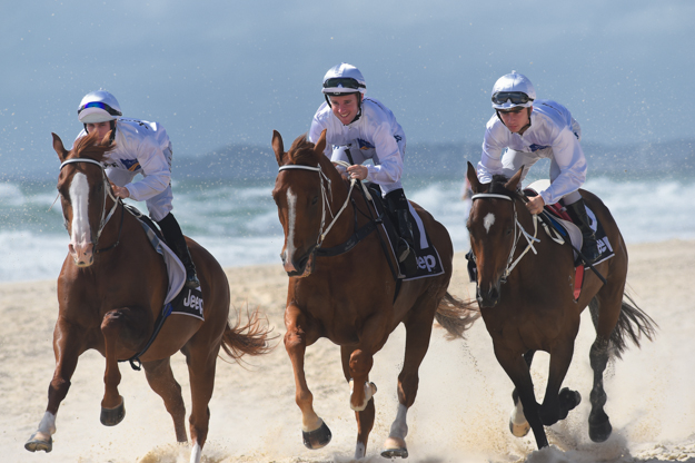 Jockeys (left-right) Brenton Avdulla, Tommy Berry and Tim Bell on Surfer's Paradise beach during the barrier draw festivities for the 2014 Magic Millions festival. Photo: Magic Millions.