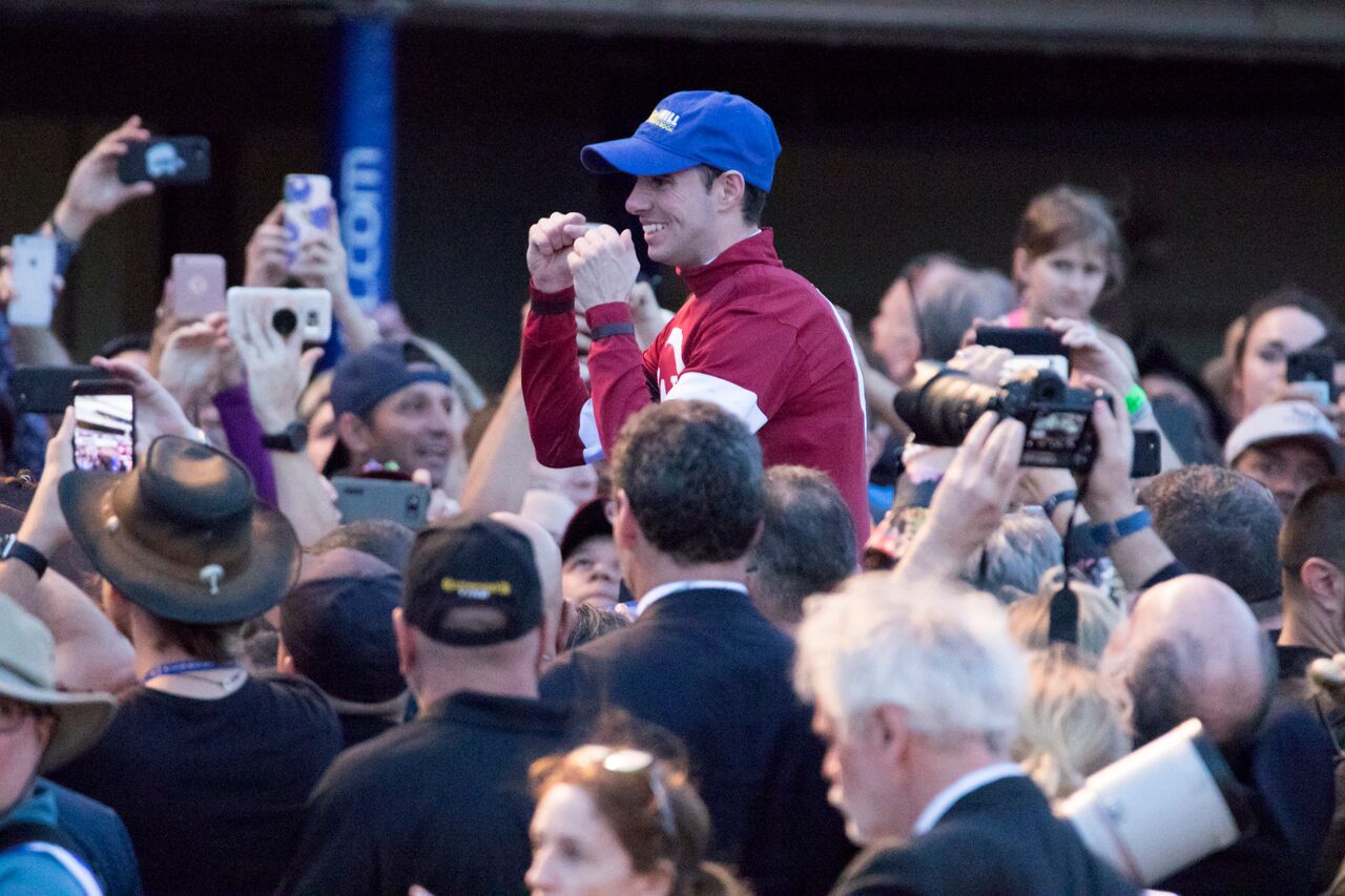 Photo shoot: Florent Geroux and Gun Runner (mainly hidden) are surrounded by racegoers as they return after their triumph. Photo: Mason Kelley