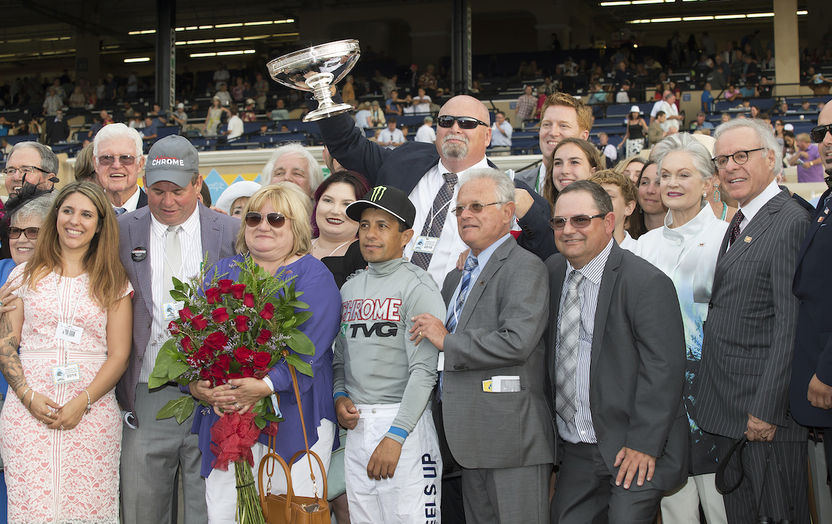 California celebration: Perry Martin holds the trophy aloft after a glorious triumph in the Pacific Classic at Del Mar. Holding the roses is his late wife Denise, with daughter Kelly’s head visible between her and jockey Victor Espinoza. Photo: Benoit