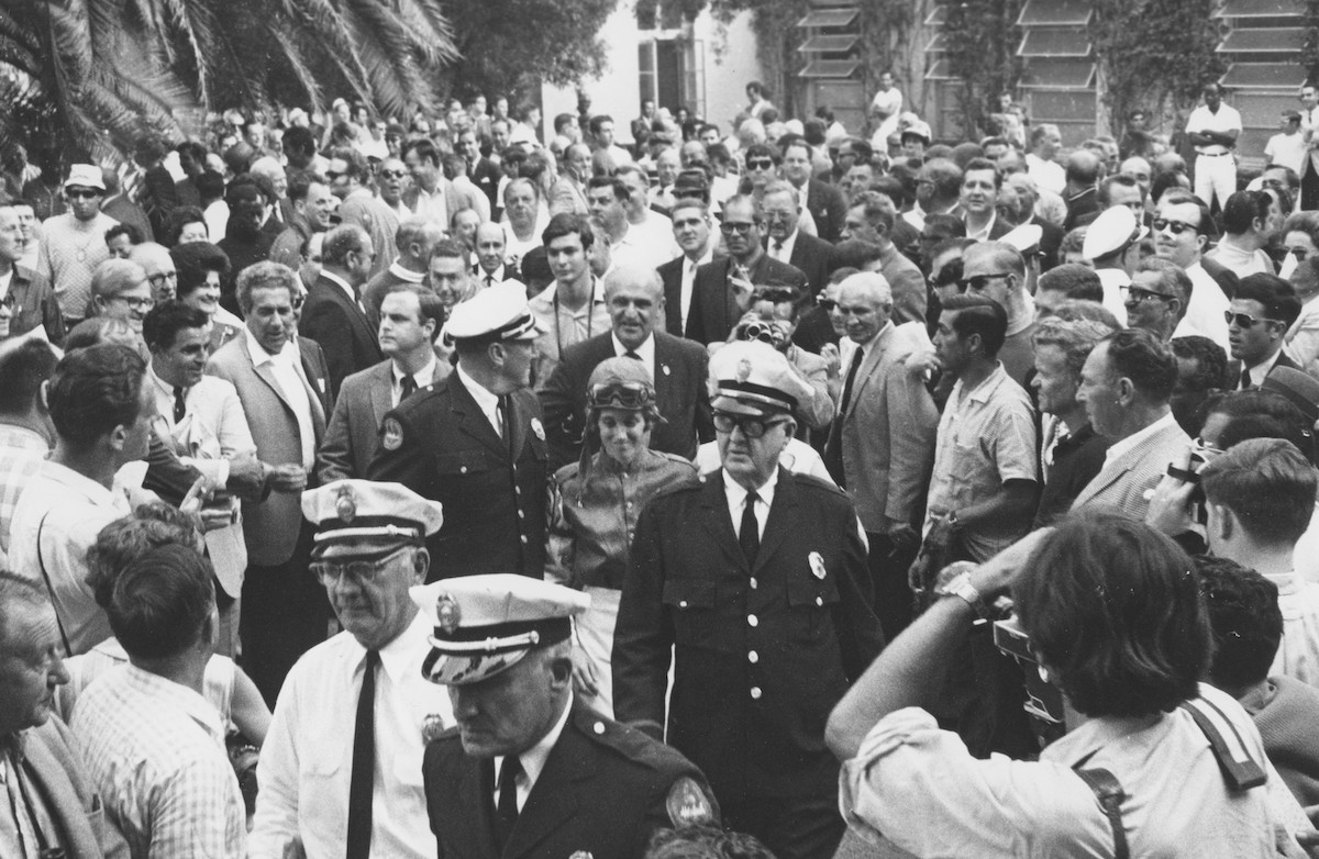 Surrounded by security personnel, Diane Crump makes her way through the virtually all-male crowd before her first race on that historic day at Hialeah Park in 1969. Photo: Jim Raftery