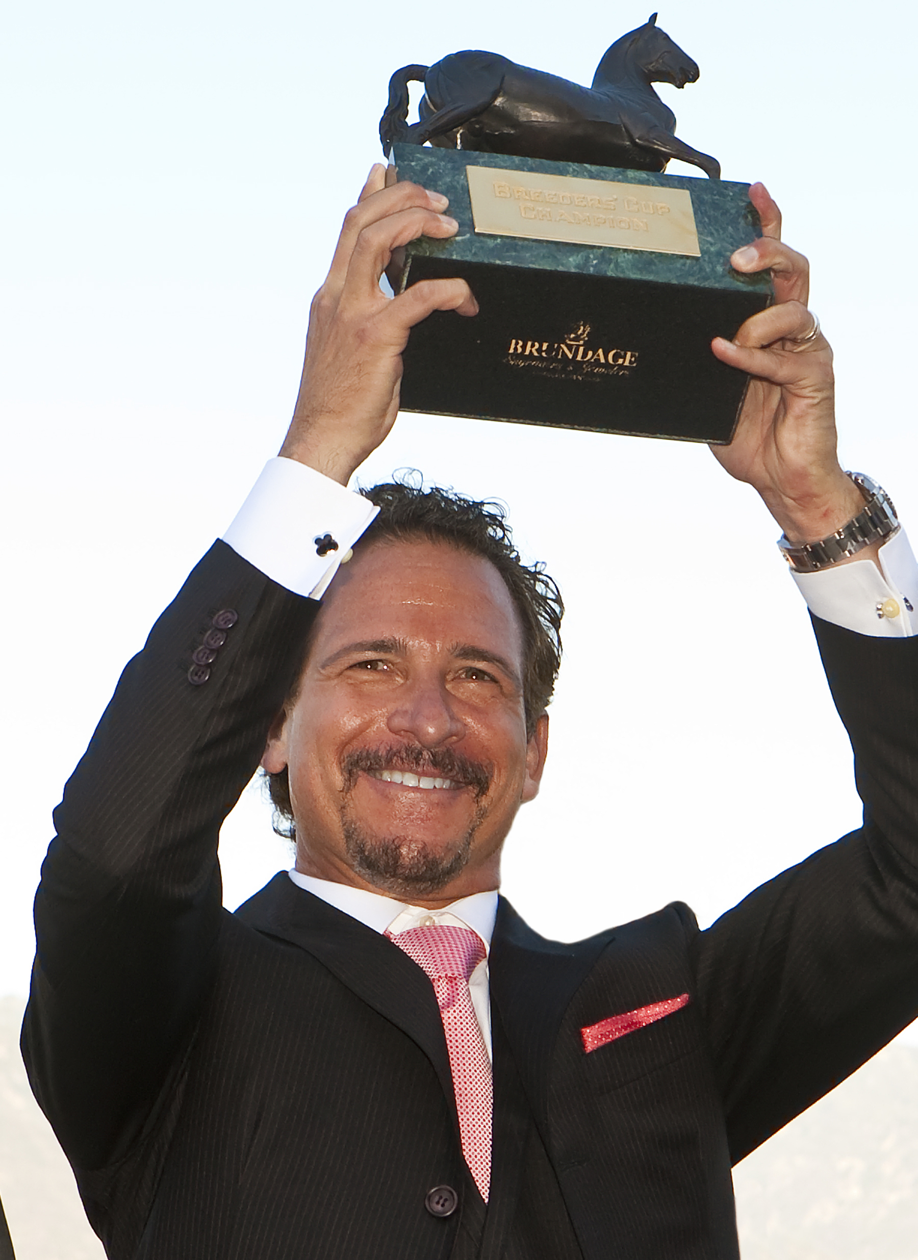 Majority owner Jim Rome raises the Breeders' Cup trophy on high. (Benoit photo)